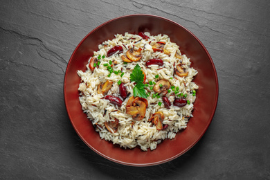 Delicious rice pilaf with mushrooms and beans on black table, top view