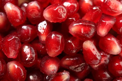 Ripe juicy pomegranate grains with water drops as background, top view