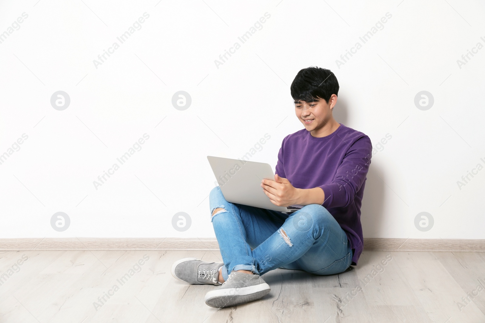 Photo of Man in casual clothes with laptop near light wall