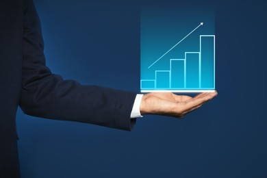 Salary increase concept. Man showing virtual image of charts and up arrow on blue background, closeup