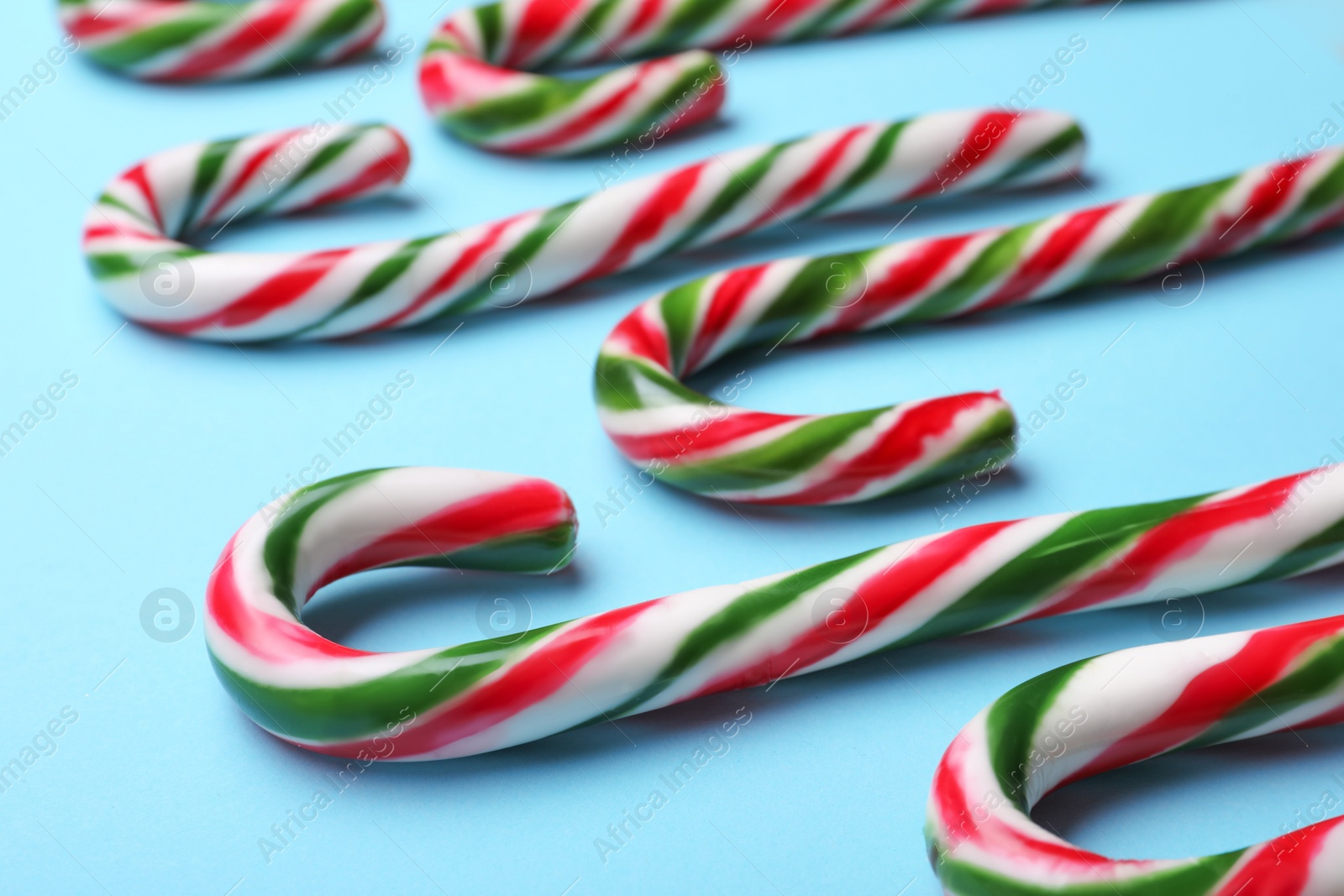 Photo of Many sweet Christmas candy canes on light blue background, closeup