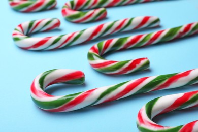 Photo of Many sweet Christmas candy canes on light blue background, closeup