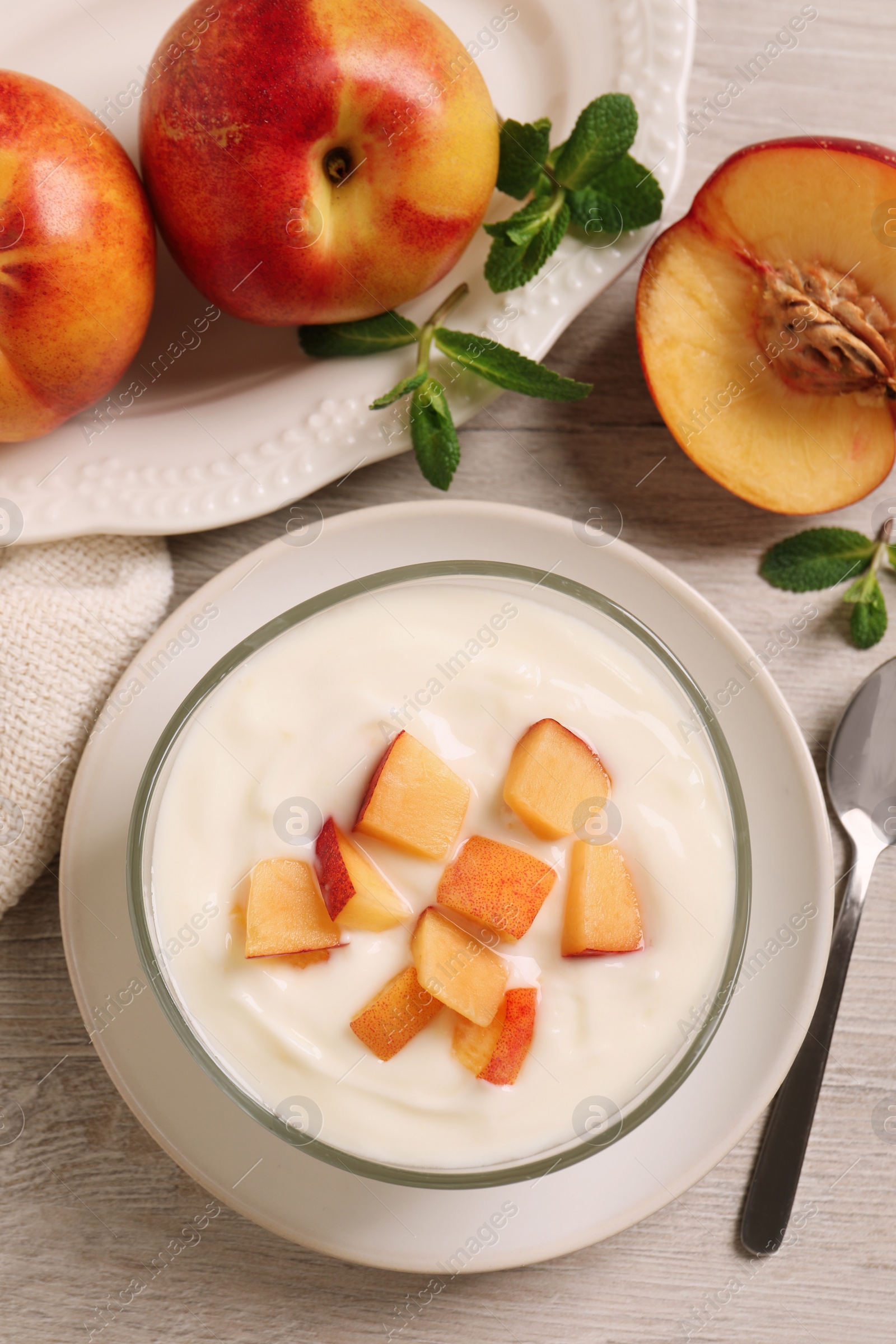 Photo of Delicious yogurt with fresh peach on light wooden table, flat lay
