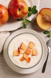 Photo of Delicious yogurt with fresh peach on light wooden table, flat lay