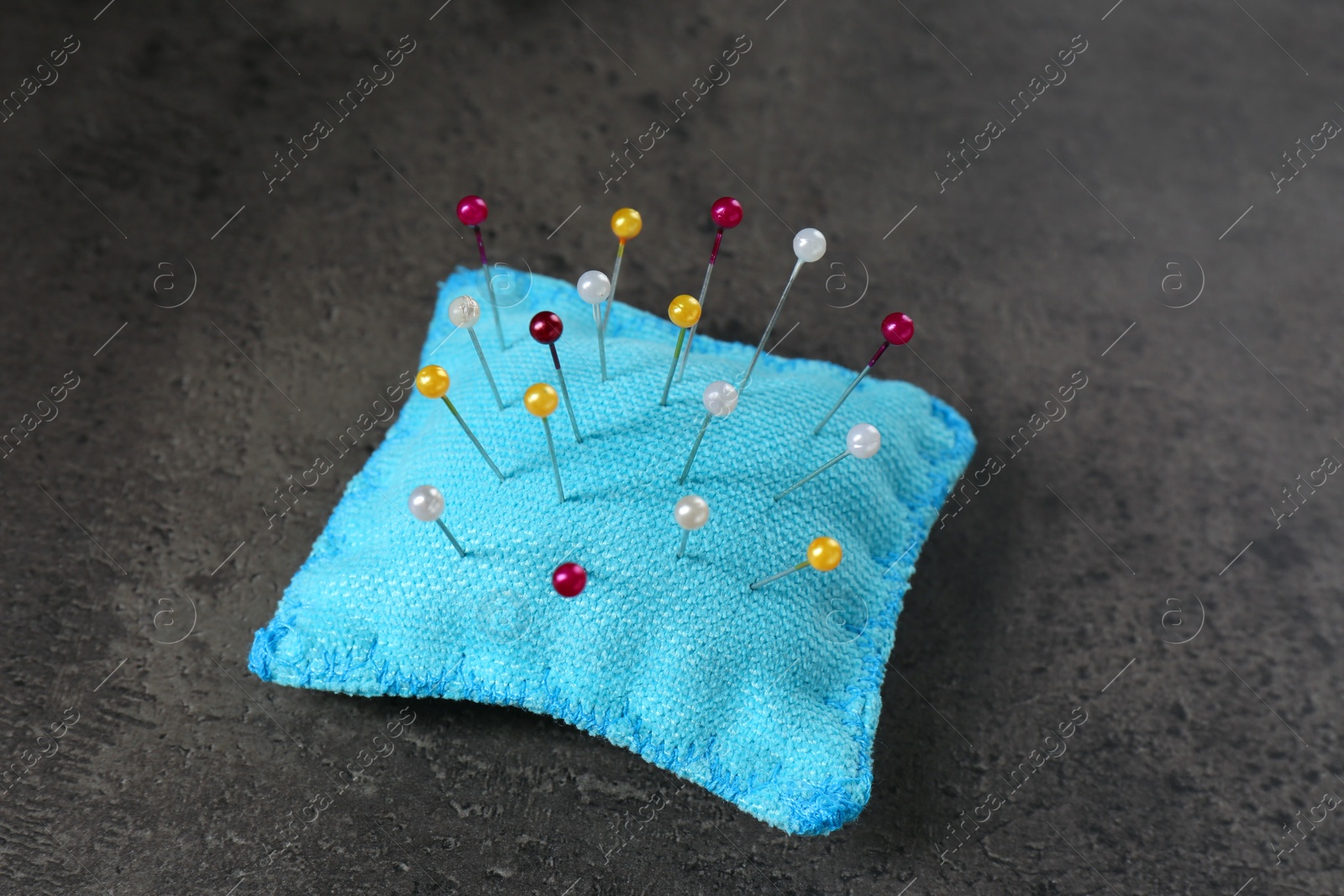 Photo of Light blue cushion with pins on grey stone table