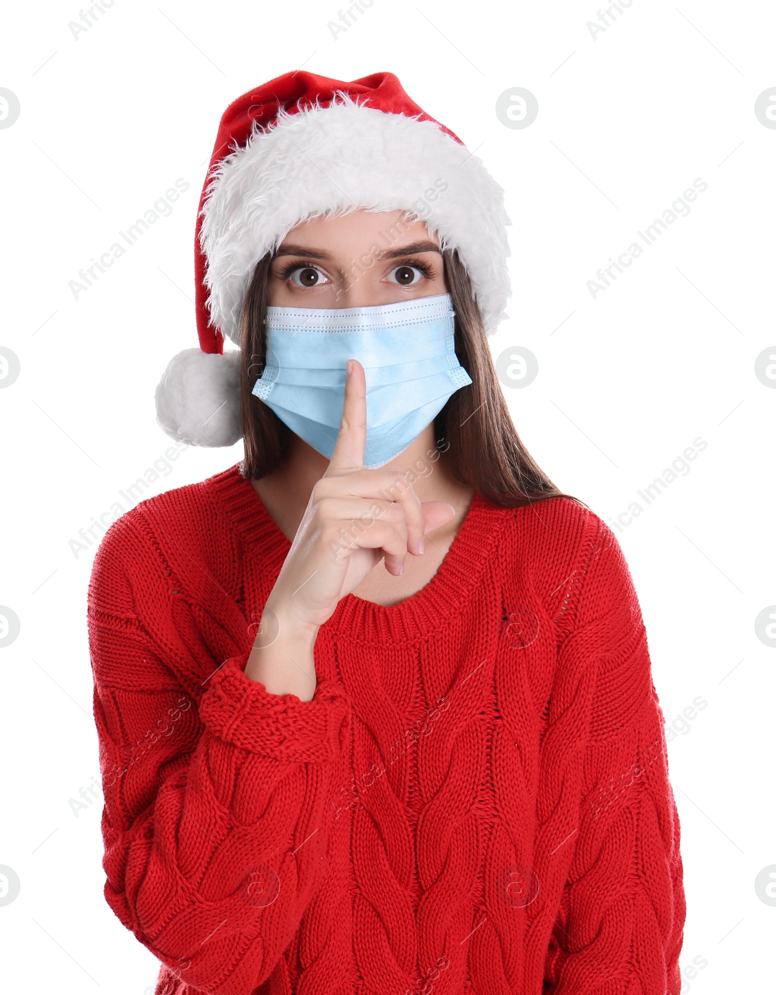 Photo of Pretty woman in Santa hat and medical mask showing silence gesture on white background