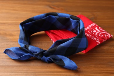 Photo of Tied and folded bandanas with different patterns on wooden table
