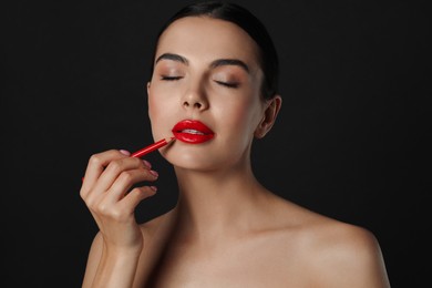 Pretty young woman with beautiful red lip pencil on black background