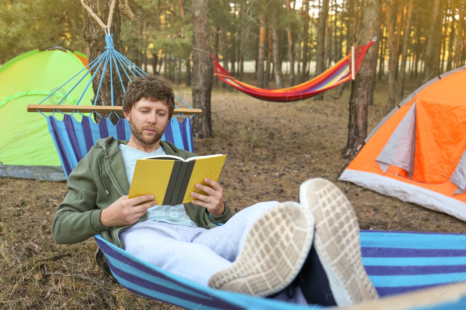 Photo of Man with book resting in comfortable hammock outdoors