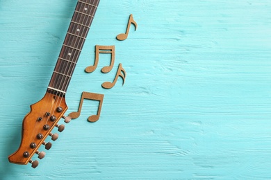 Photo of Guitar neck and music notes on wooden background, flat lay. Space for text