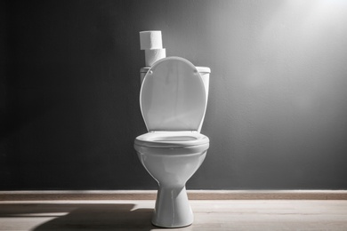 Photo of New ceramic toilet bowl near grey wall, side light