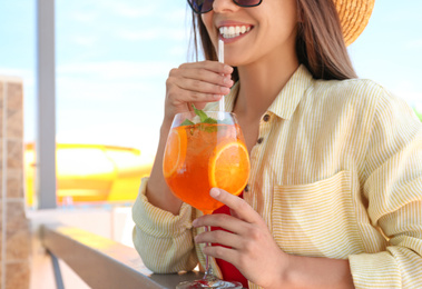 Woman with glass of refreshing drink outdoors, closeup