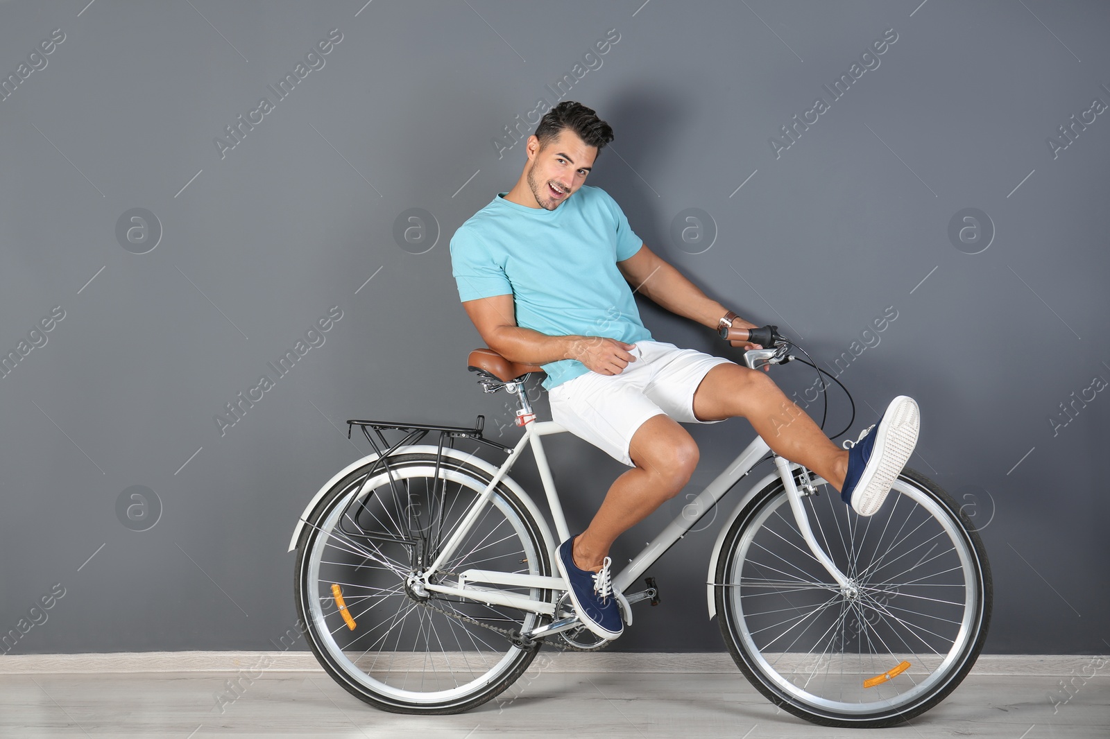 Photo of Handsome young hipster man with bicycle near color wall