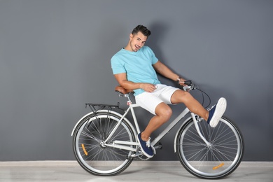 Photo of Handsome young hipster man with bicycle near color wall