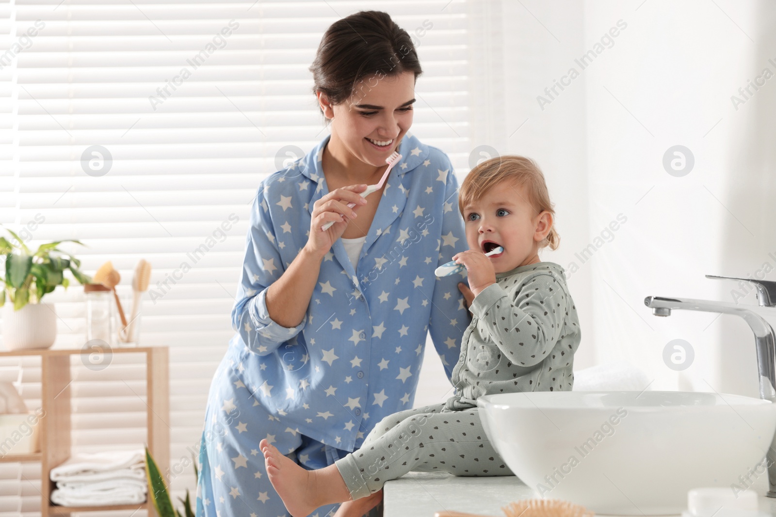 Photo of Mother and her daughter brushing teeth together in bathroom