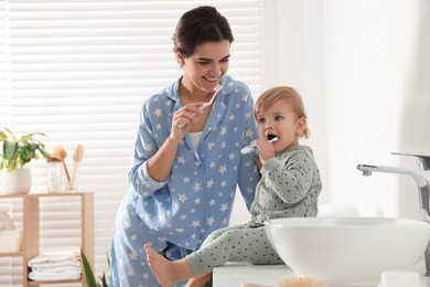 Mother and her daughter brushing teeth together in bathroom