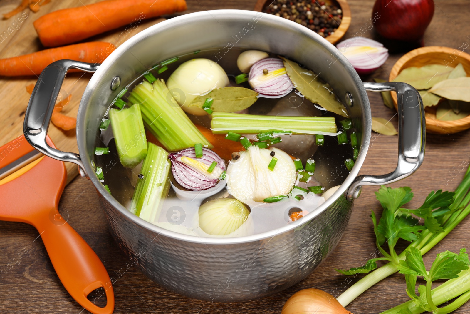 Photo of Pot and different ingredients for cooking tasty bouillon on wooden table