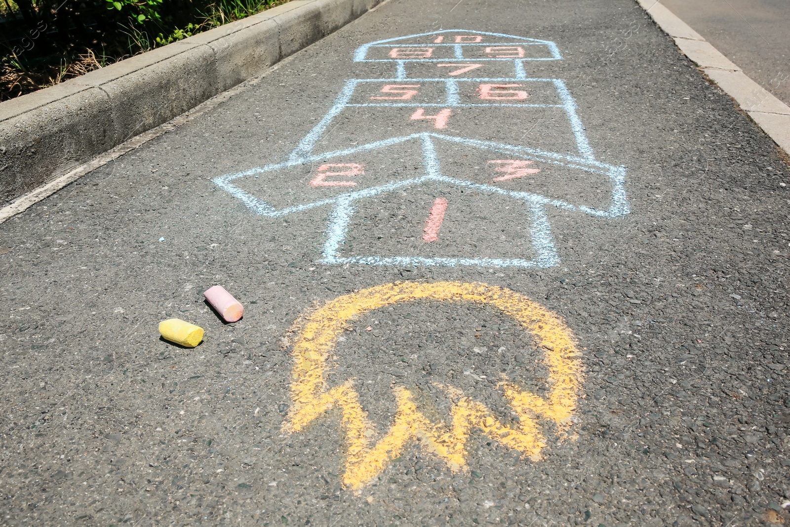 Photo of Hopscotch drawn with colorful chalk on asphalt outdoors, closeup