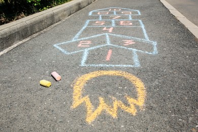 Photo of Hopscotch drawn with colorful chalk on asphalt outdoors, closeup