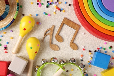 Photo of Baby song concept. Wooden notes, kids musical instruments and toys on beige carpet, flat lay
