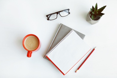 Photo of Composition with cup of coffee, plant and notebooks on white background, top view. Space for mockup