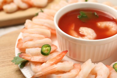 Photo of Tasty boiled shrimps with cocktail sauce, chili and parsley on table, closeup