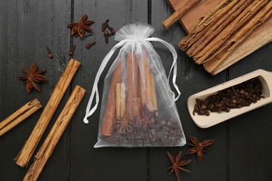 Photo of Scented sachet with cinnamon sticks and anise stars on wooden table, flat lay