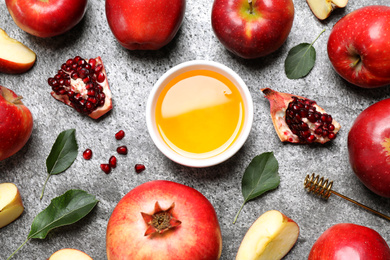 Photo of Honey, apples and pomegranates on grey table, flat lay. Rosh Hashanah holiday