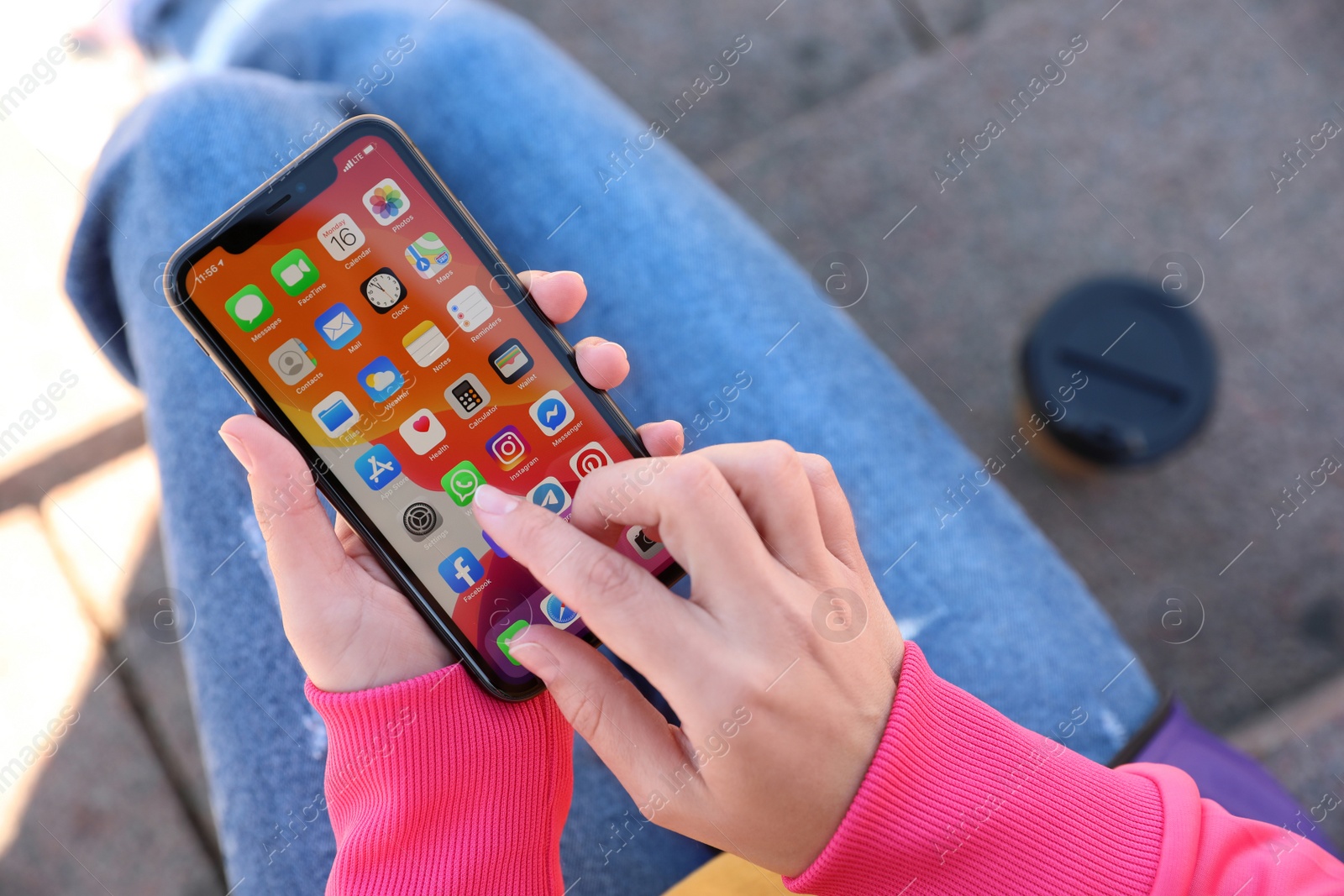 Photo of MYKOLAIV, UKRAINE - MARCH 16, 2020: Woman holding iPhone 11 with home screen outdoors, closeup