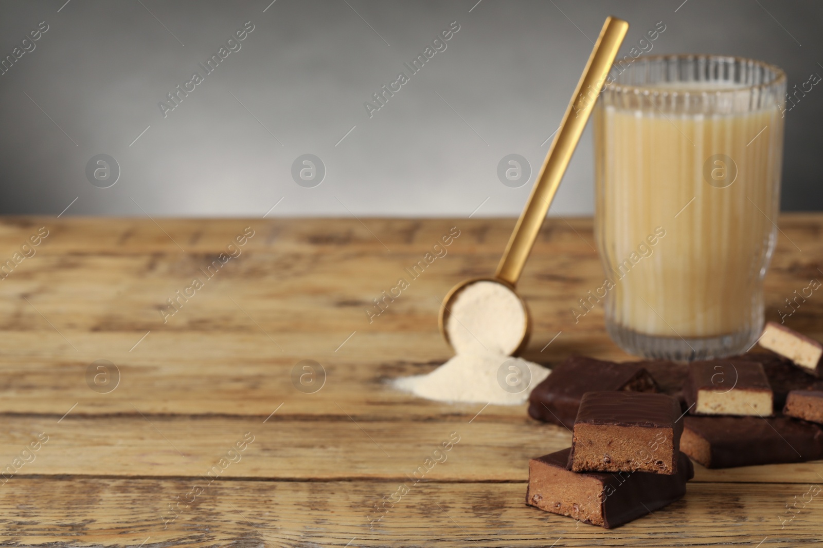 Photo of Different energy bars, protein cocktail and powder on wooden table. Space for text