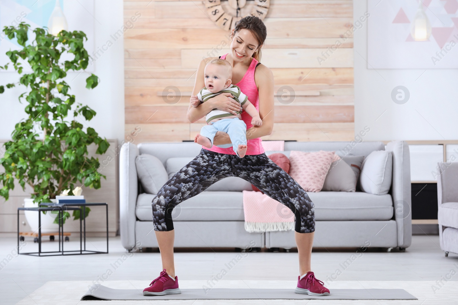 Photo of Young sportive woman doing exercise with her son at home. Fitness training