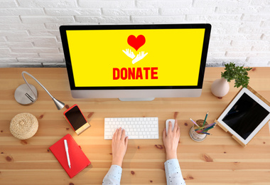 Image of Donations concept. Woman working with computer at wooden table, closeup