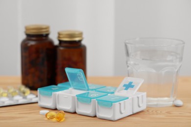 Photo of Plastic pill box and different medicaments on wooden table