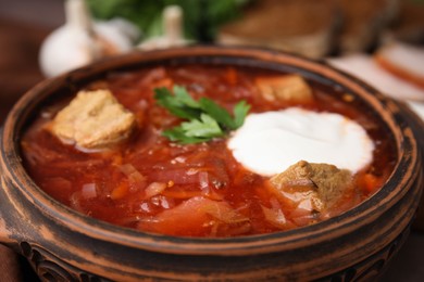 Photo of Tasty borscht with sour cream in bowl, closeup