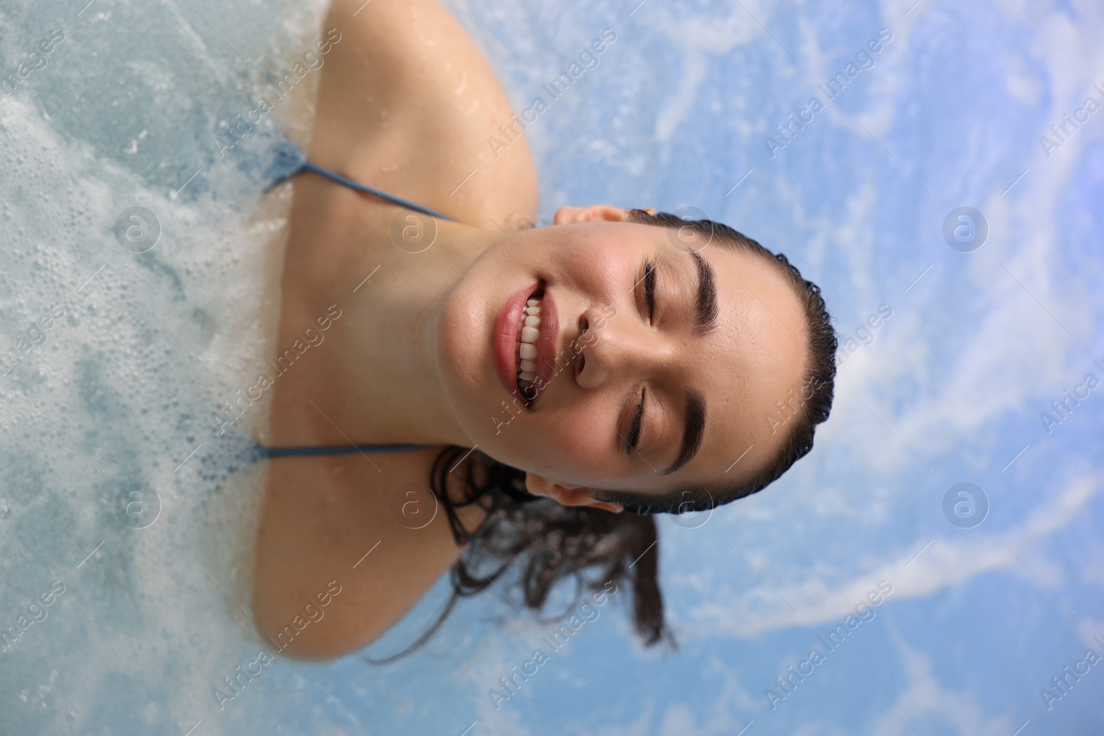 Photo of Beautiful woman relaxing in spa swimming pool, top view