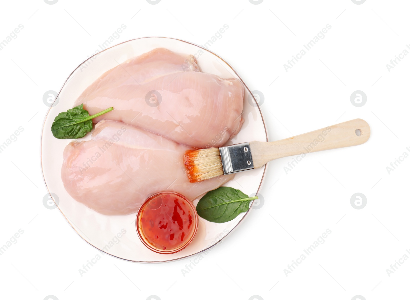 Photo of Marinade, basting brush and raw chicken fillets isolated on white, top view