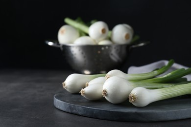 Photo of Whole green spring onions on black table, closeup