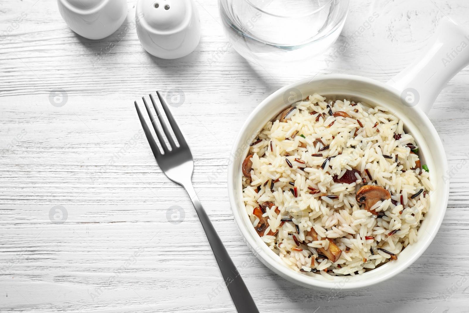 Photo of Delicious rice pilaf with mushrooms on white wooden table, flat lay