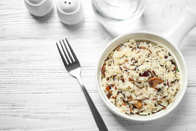 Delicious rice pilaf with mushrooms on white wooden table, flat lay