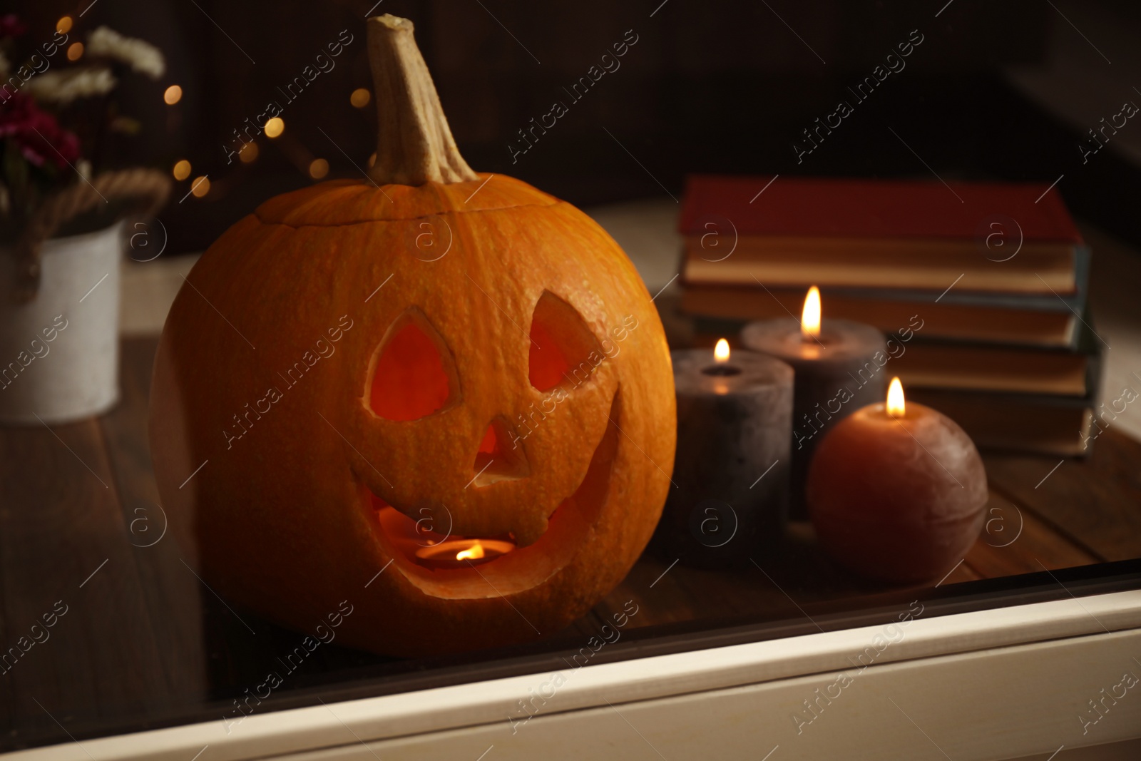 Photo of Composition with pumpkin head on windowsill, view through glass. Jack lantern - traditional Halloween decor