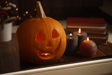 Photo of Composition with pumpkin head on windowsill, view through glass. Jack lantern - traditional Halloween decor
