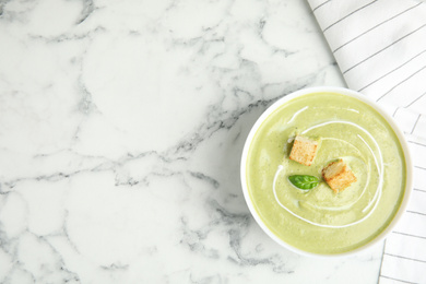 Photo of Delicious broccoli cream soup with croutons served on white marble table, top view. Space for text