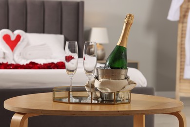 Photo of Honeymoon. Sparkling wine and glasses on wooden table in room