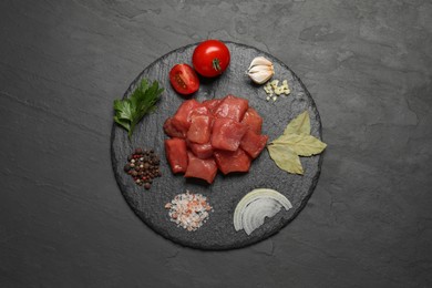 Photo of Raw beef meat and different ingredients for cooking delicious goulash on black table, top view