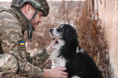 Ukrainian soldier petting frightened stray dog outdoors
