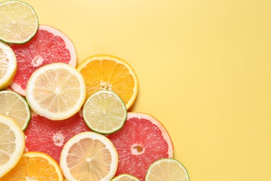 Photo of Different sliced citrus fruits on yellow table, top view. Space for text