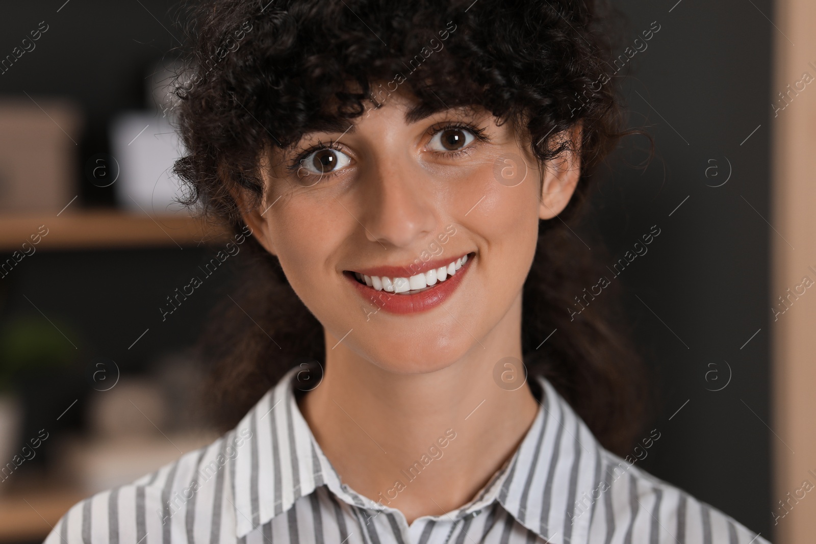 Photo of Portrait of beautiful woman with curly hair on blurred background. Attractive lady smiling and looking into camera