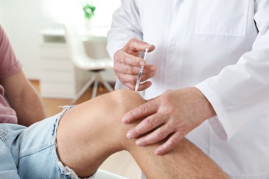 Photo of Doctor giving patient injection in clinic, closeup. Knee problem treatment