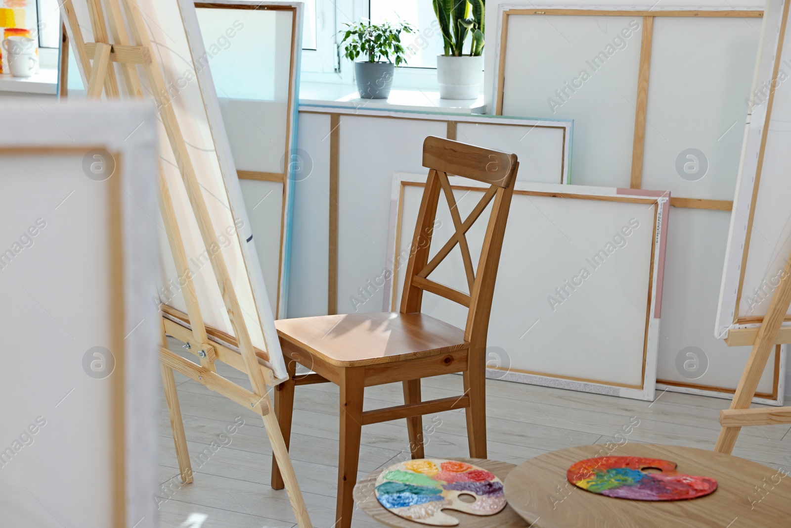 Photo of Easel with canvas and chair near window in artist's studio. Creative hobby