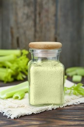 Natural celery powder in jar and fresh stalks on wooden table